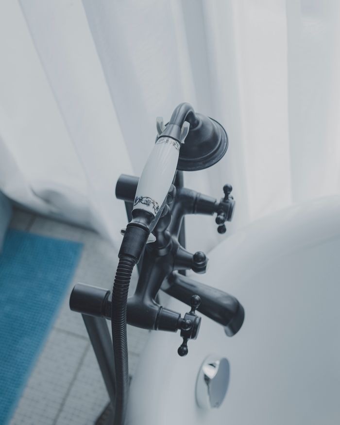 About Close-up view of a stylish black faucet with a showerhead on a bathtub.